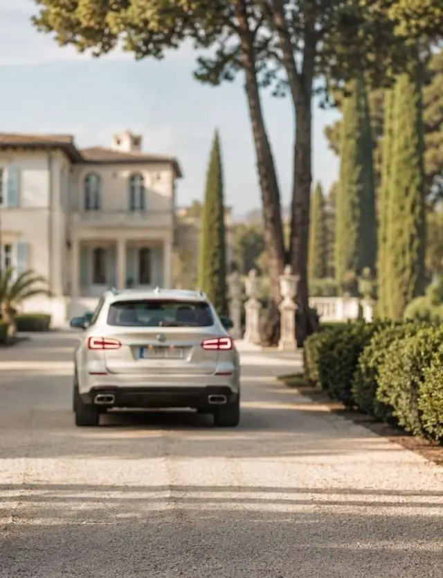 Vehicle arriving along a cypress-lined drive to a Riviera property